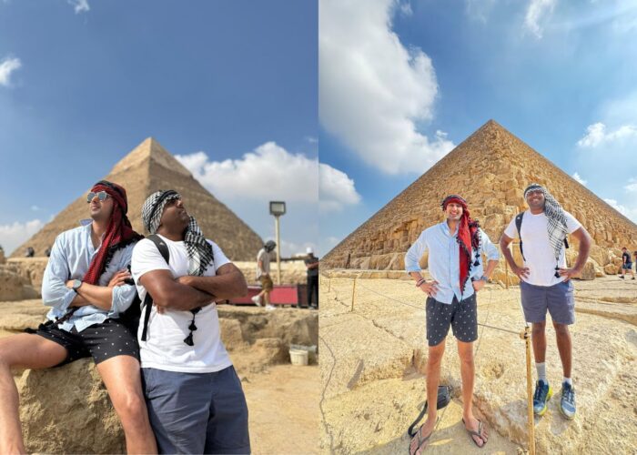 Two happy visitors on a sunny Egypt tour posing for a picture in traditional headscarves at the Giza Pyramids in Egypt.