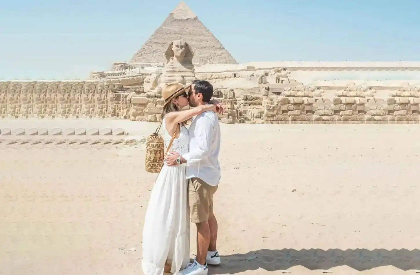 Couple kissing on a romantic honeymoon in front of the Great Sphinx and Pyramids of Giza in Egypt in October.